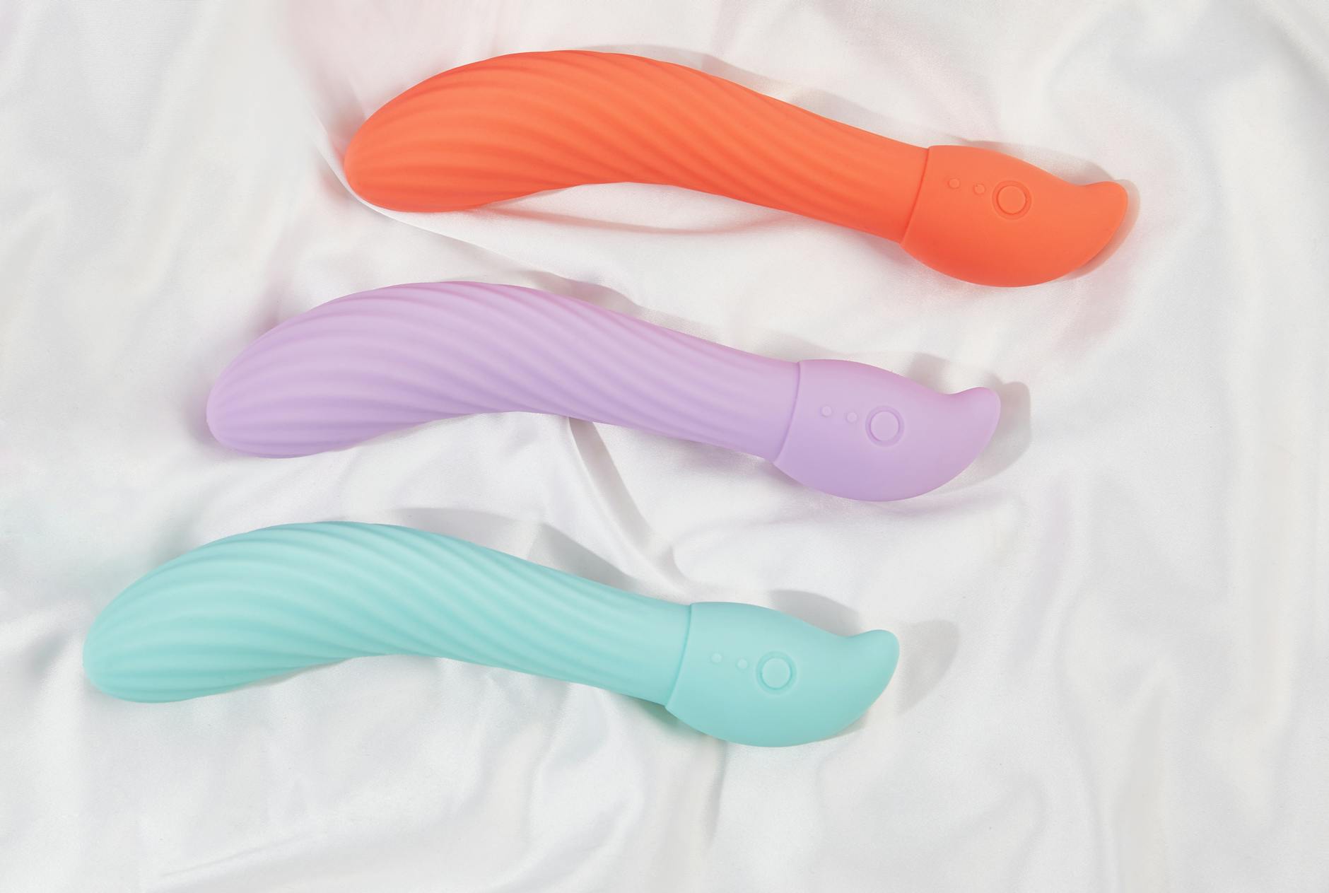A stylish teal vibrator on smooth white silk fabric, representing intimate wellness and personal pleasure