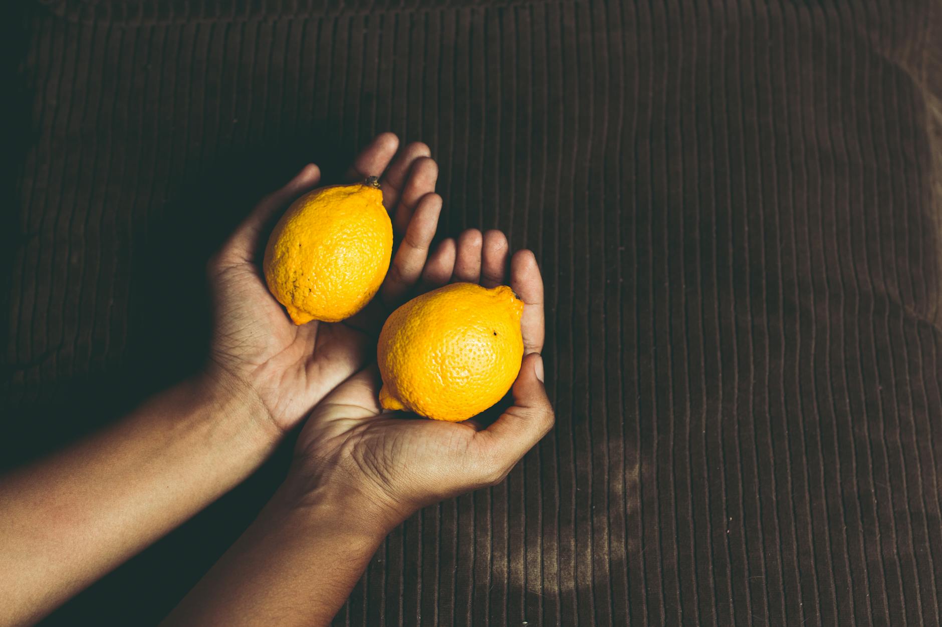 Two fresh lemons held in cupped hands, symbolizing natural pleasure and renewal
