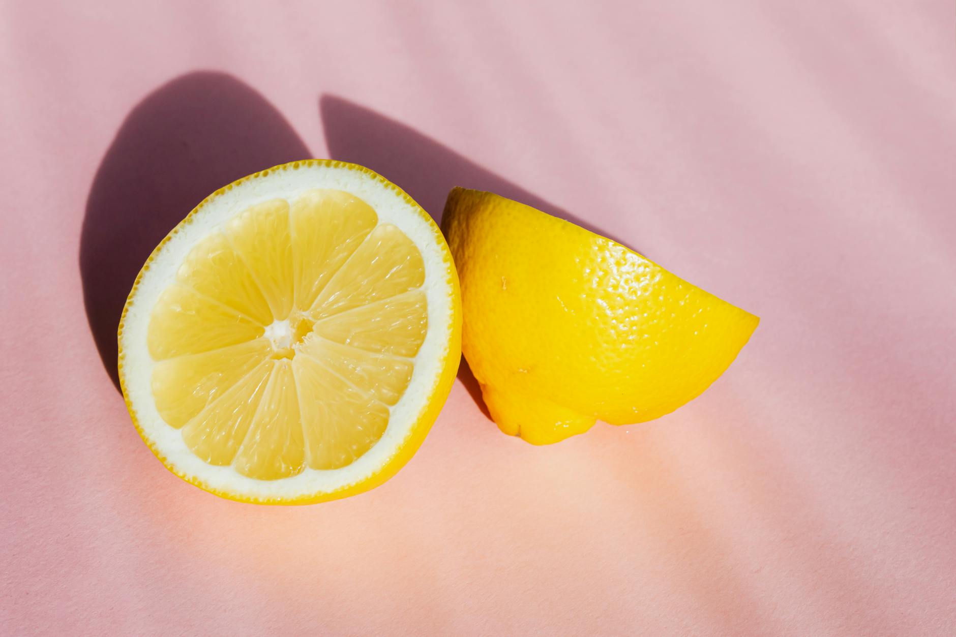 Fresh lemon halves on a pink background in sunlight, symbolizing renewal and clarity