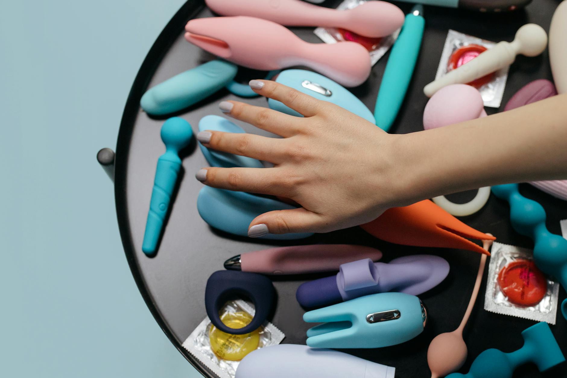 Hand holding an orange vibrator against a minimalistic purple backdrop