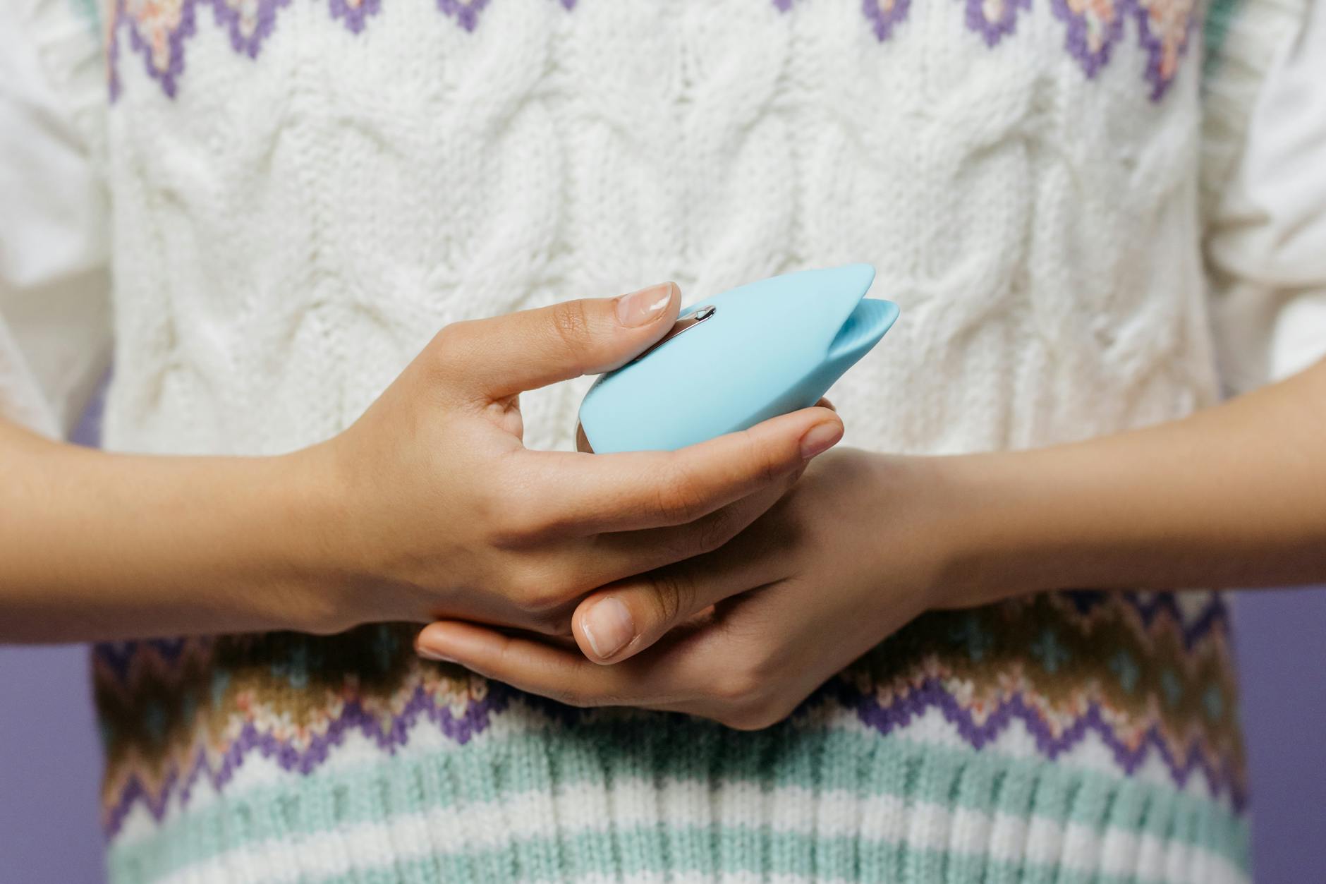 Hands holding a blue personal massager, representing support and intimacy during anxiety.